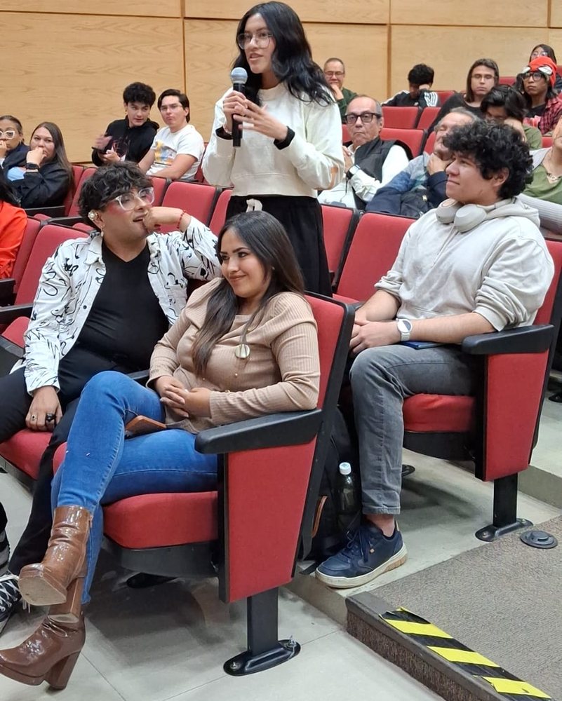 A live AhaSlides quiz at an event: a full lecture hall, with a student answering a question into a microphone